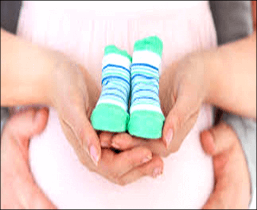 Mãe segurando sapatinhos de nenê