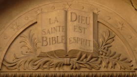 Escultura de um pórtico com uma Bíblia aberta em que se lê Dieu est Espirit.
